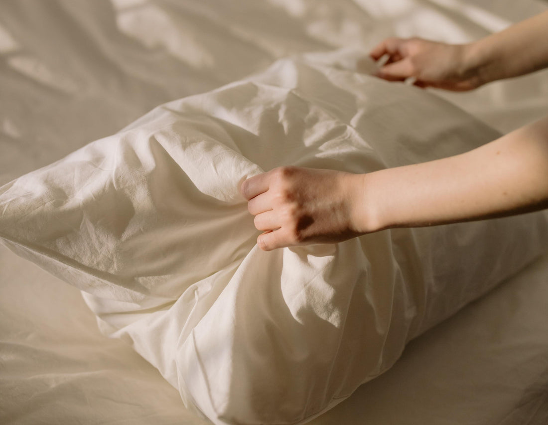 hand fixing a white pillow